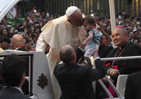 Pope Francis kisses baby while greeting crowd of faithful from popemobile in downtown Rio de Janeiro
