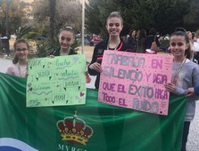 Las 4 gimnastas con bandera y carteles hechos por sus compañeras del club