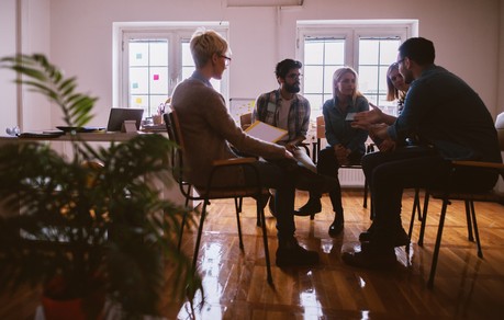 Young people with problems having a discussion while sitting together on special group therapy.