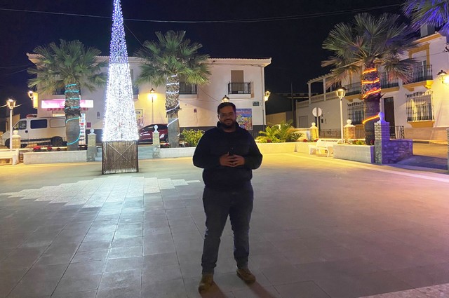 DOMINGO TRABALÓN EN UNA PLAZA DE ZURGENA CON COMERCIOS AL FONDO