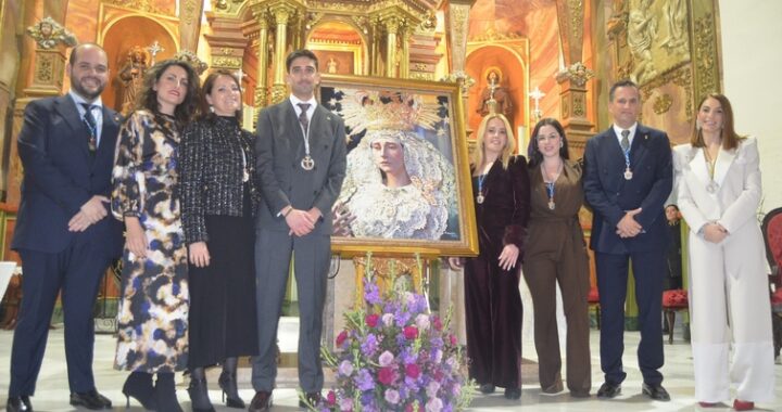 El Pregonero y la Hermana Mayor del Paso Blanco junto al equipo de gobierno posan junto al Cartel de Semana Santa 2026